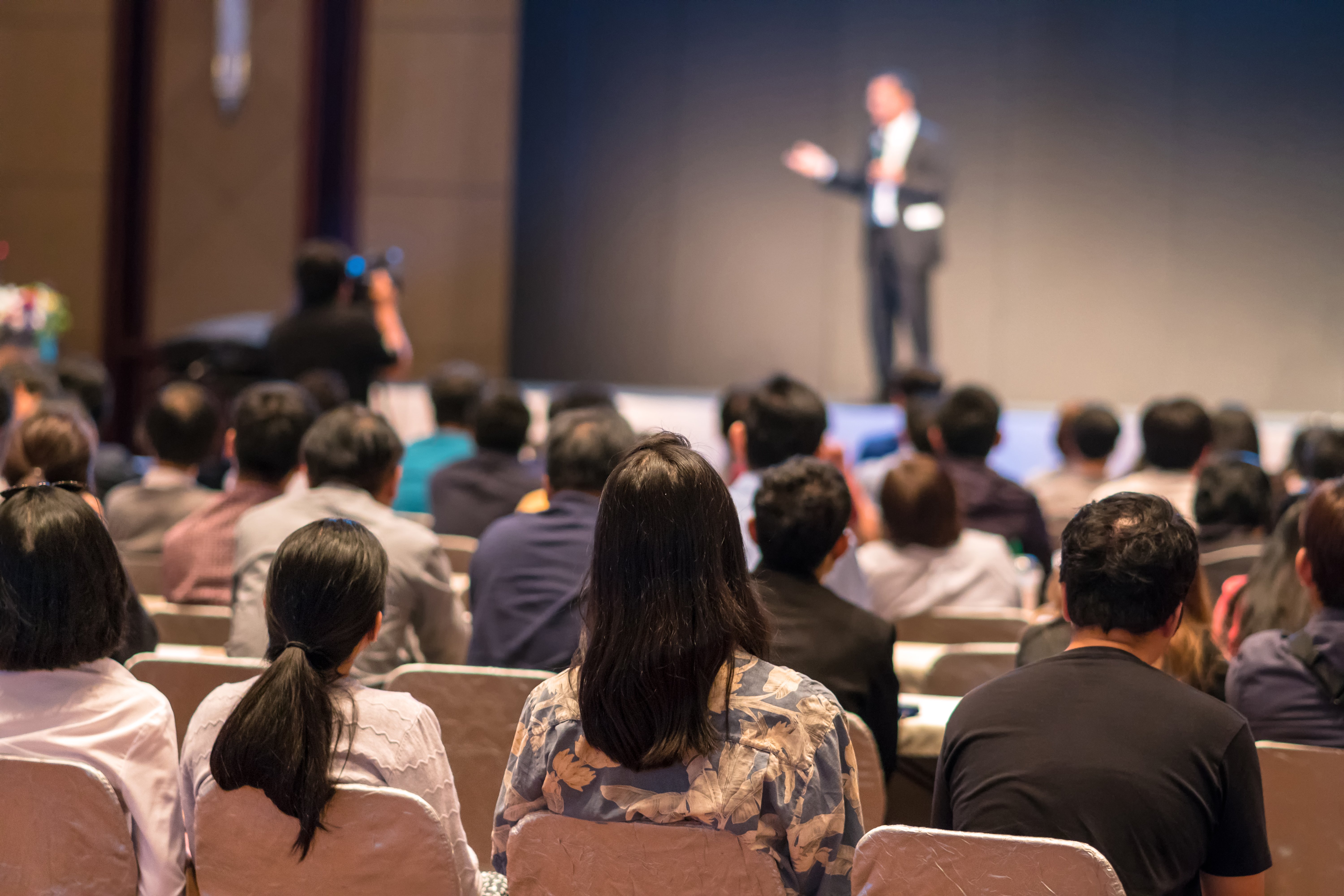 rear-side-audiences-sitting-listening-speackers-stage-1